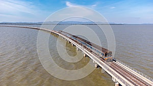 Aerial view of an amazing travel train parked on a floating railway bridge over the water of the lake in Pa Sak Jolasid dam with b