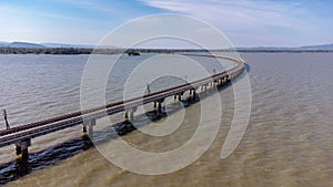 Aerial view of an amazing travel train parked on a floating railway bridge over the water of the lake in Pa Sak Jolasid dam with b