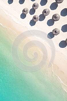 Aerial view of amazing tropical white sandy beach with palm leaves umbrellas and turquoise sea.