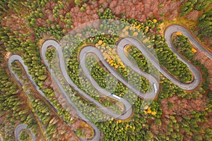 Aerial view of an amazing winding curved road through the mountains in autumn fall colors landscape, motorway in Romania