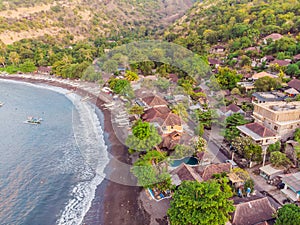 Aerial view of Amed beach in Bali, Indonesia. Traditional fishing boats called jukung on the black sand beach and Mount