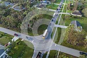 Aerial view of american yellow school bus picking up children at sidewalk bus stop for their lessongs in early morning