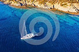 Aerial view of anchored sailing yacht in emerald sea. Aerial view of a boat. Outdoor water sports, yachting. Aerial view of