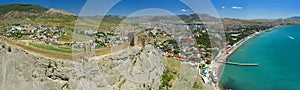 Aerial view on ancient stone castle on the top of the stone rock with city, blue sea and mountains in the background. Cenevez Qaya