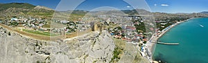 Aerial view on ancient stone castle on the top of the stone rock with city, blue sea and mountains in the background. Cenevez Qaya