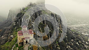 Aerial view of ancient temple on top of mountain. White walls of structure are visible on top of mountain among bright
