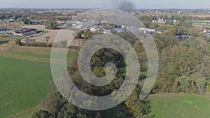 Aerial view of an antique restored steam engine in farmlands blowing black smoke with a head on view