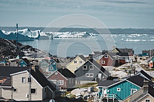 Aerial View of Arctic city of Ilulissat, Greenland. Colorful houses in the center of the town with icebergs in the