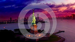Aerial view around glowing statue of liberty, during a colorful sunset, dark clouds rolling in, in New York, USA - Orbit