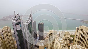 Aerial view of the array of skyscrapers facing the sea in the small fog. Dubai, United Arab Emirates