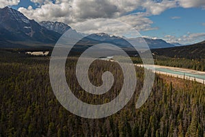 Aerial view of the Athabasca River with its bluish color surrounded by thousands of trees and high mountains of the Canadian