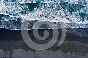 Aerial view of Atlantic ocean waves washing black sandy beach