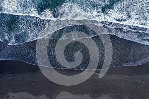 Aerial view of Atlantic ocean waves washing black sandy beach