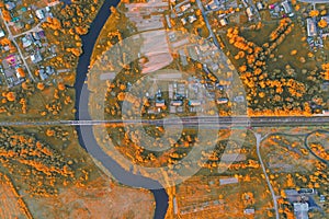 Aerial view autumn landscape of winding small river among the town, stream in orange colors nature field, top view