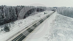 Aerial view of a b freight truck driving down a highway running along a railroad on a clear winter day. Cargo trucks