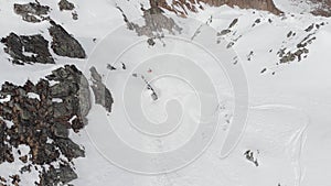 Aerial view of a backcountry skier rides in orange clothes freeride on a steep slope makes drop jump. Professional ski