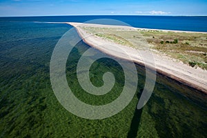 Aerial view. Baltic sea sand spit. Clear transparent water and shadow of lighthouse. Blue sky.