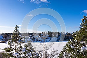 Aerial view of the Bay of the Baltic sea with rocky coasts in winter day. Winter snowy landscape of the Swedish coast on blue sky