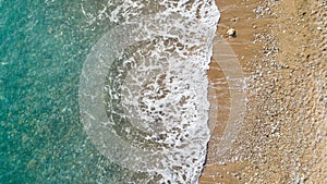 Aerial view of beach with ocean waves reaching shore. Beautiful turquoise water.