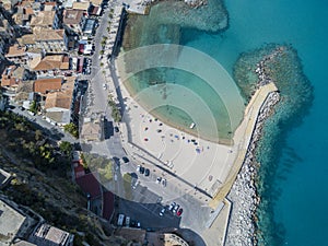 Aerial view of a beach and a pier with canoes, boats and umbrellas.