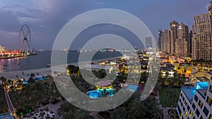 Aerial view of beach and tourists walking in JBR with skyscrapers day to night timelapse in Dubai, UAE