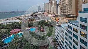 Aerial view of beach and tourists walking in JBR with skyscrapers day to night timelapse in Dubai, UAE