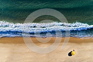 Aerial view of beach umbrella with a person sunbathing, at the Comporta Beach in Portugal.