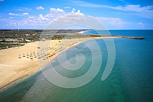 Aerial view of a beach with umbrellas, blue sky and water and golden sand