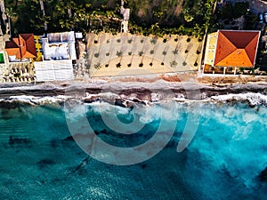Aerial view of beach and waves. Turquoise sea water and palms, summer landscape from above