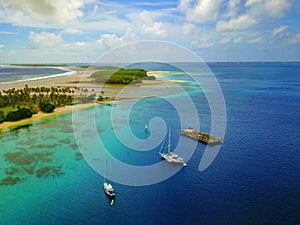 Aerial view of a beautiful atoll with village and moored yachts