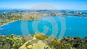 Aerial view on beautiful bay at sunny day with sandy beach and residential houses on the background. Waiheke Island, Auckland, New