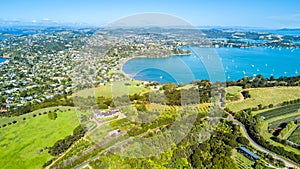 Aerial view on beautiful bay at sunny day with sandy beach and residential houses on the background. Waiheke Island, Auckland, New