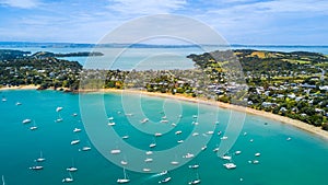 Aerial view on beautiful bay at sunny day with sandy beach and residential suburbs on the background. Waiheke Island, Auckland, Ne