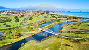 Aerial view on a beautiful bridge across a small river with residential suburb and Tasman sea on the background. New Zealand