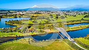 Aerial view on a beautiful bridge across a small stream with Mount Taranaki on the background. New Zealand