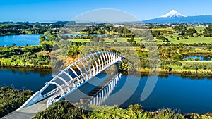 Aerial view on a beautiful bridge across a small stream with Mount Taranaki on the background. New Zealand photo