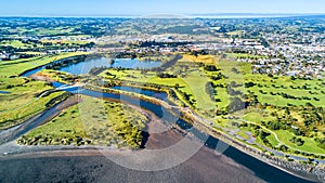 Aerial view on a beautiful bridge across a small stream with residential suburb on the background. New Zealand