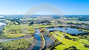 Aerial view on a beautiful bridge across a small stream with residential suburb on the background. New Zealand