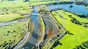 Aerial view on a beautiful bridge across a small stream with residential suburb on the background. New Zealand