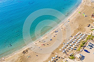 Aerial view of beautiful Coral beach in Paphos with azure seawater, Cyprus. Sand coast with umbrellas, sunbeds, people