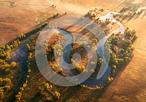 Aerial view of beautiful curving river in fog in autumn