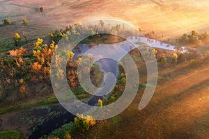 Aerial view of beautiful curving river in fog in autumn