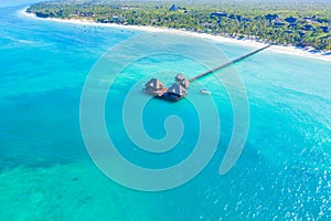 Aerial view of beautiful hotel in Indian ocean at sunset in summer. Zanzibar, Africa. Top view. Landscape with wooden hotel on the