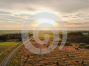 Aerial view beautiful panoramic landscape golden sunset above the forest. The road goes beyond the horizon in the rays of the sun