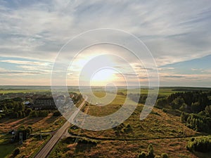 Aerial view beautiful panoramic landscape golden sunset above the forest. The road goes beyond the horizon in the rays of the sun