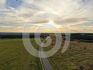 Aerial view beautiful panoramic landscape golden sunset above the forest. The road goes beyond the horizon in the rays of the sun