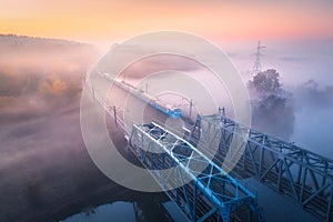 Aerial view of beautiful railroad bridge and river in fog in fall