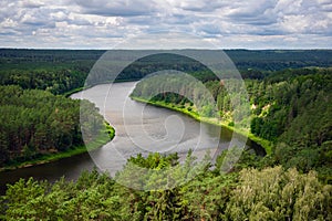 Aerial view of beautiful river Nemunas surrounded by pine forest in Lithuania. Birdseye view of nature scene on a sunny day