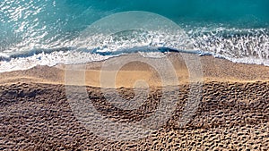 Aerial view of beautiful sandy beach with footprints and soft turquoise ocean wave. Tropical sea in summer season on Kathisma