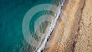 Aerial view of beautiful sandy beach with footprints and soft turquoise ocean wave. Tropical sea in summer season on Kathisma